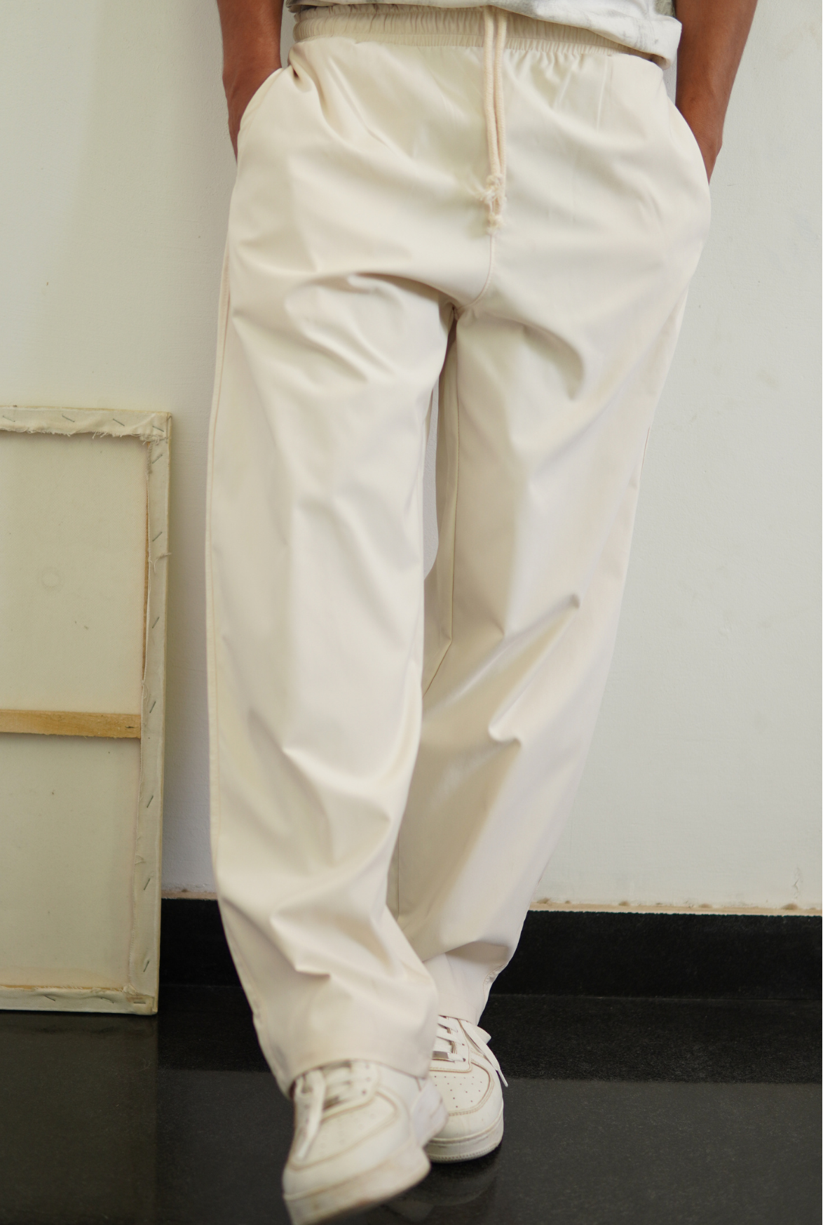 Person wearing beige pants and white sneakers in a minimal indoor setting
