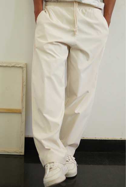 Person wearing beige pants and white sneakers in a minimal indoor setting