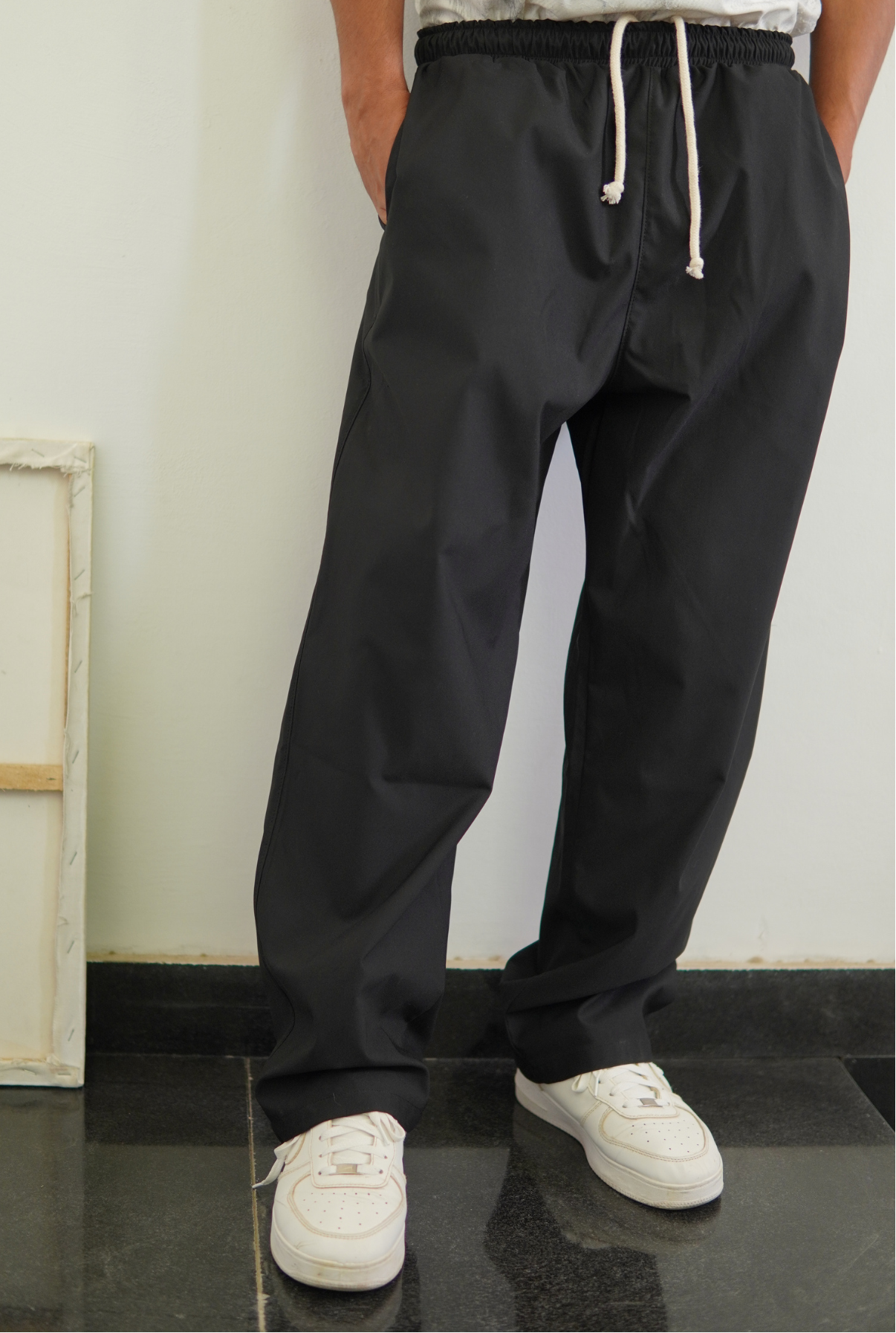 Person wearing black drawstring pants with a white background