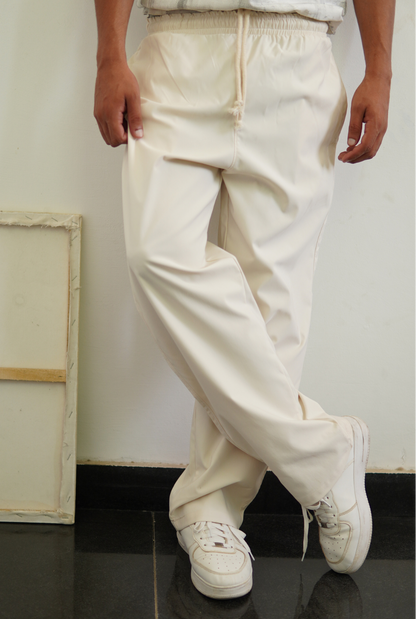 Person wearing white pants and white sneakers in a minimal indoor setting